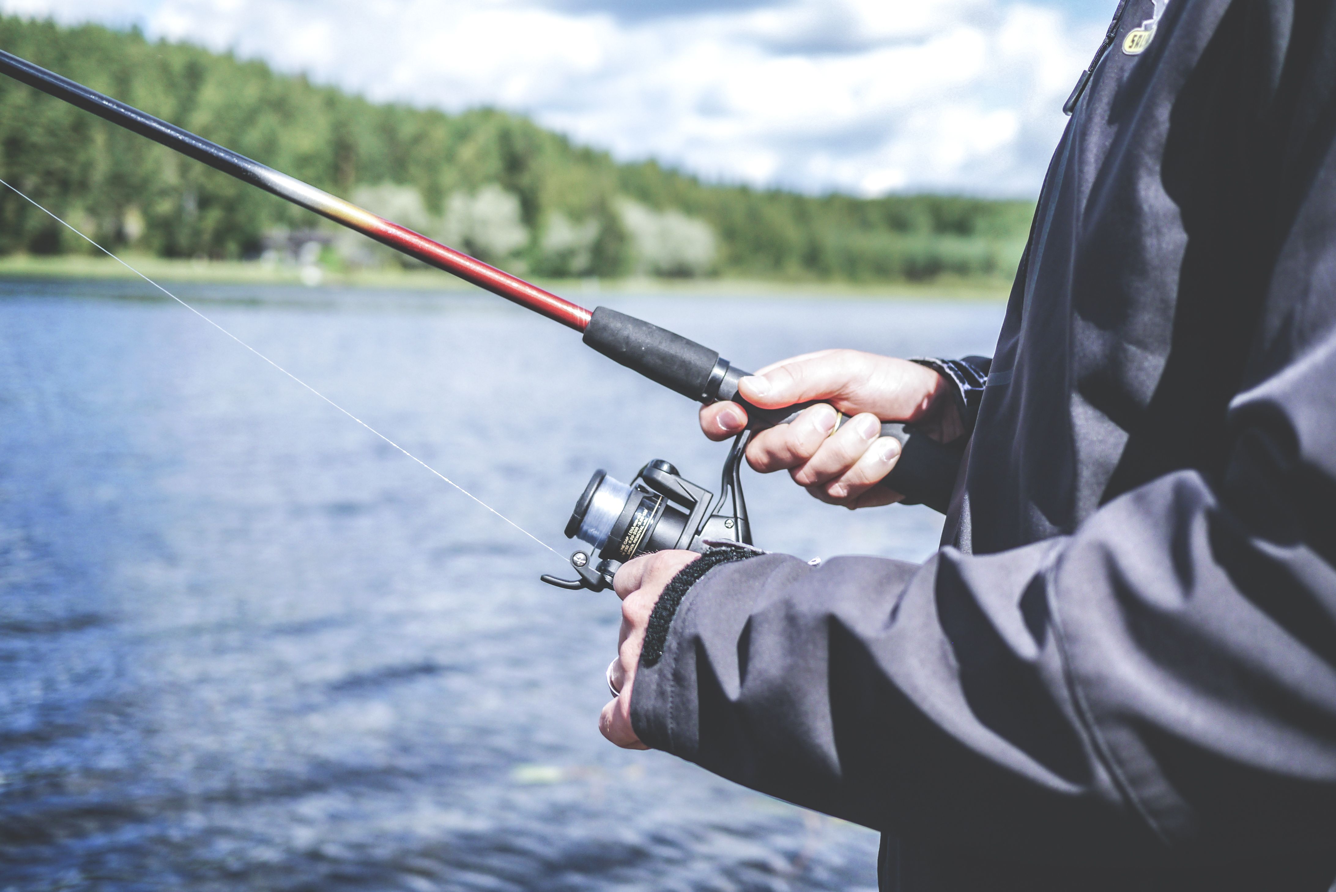 Person fishing at lakeside in warm weather