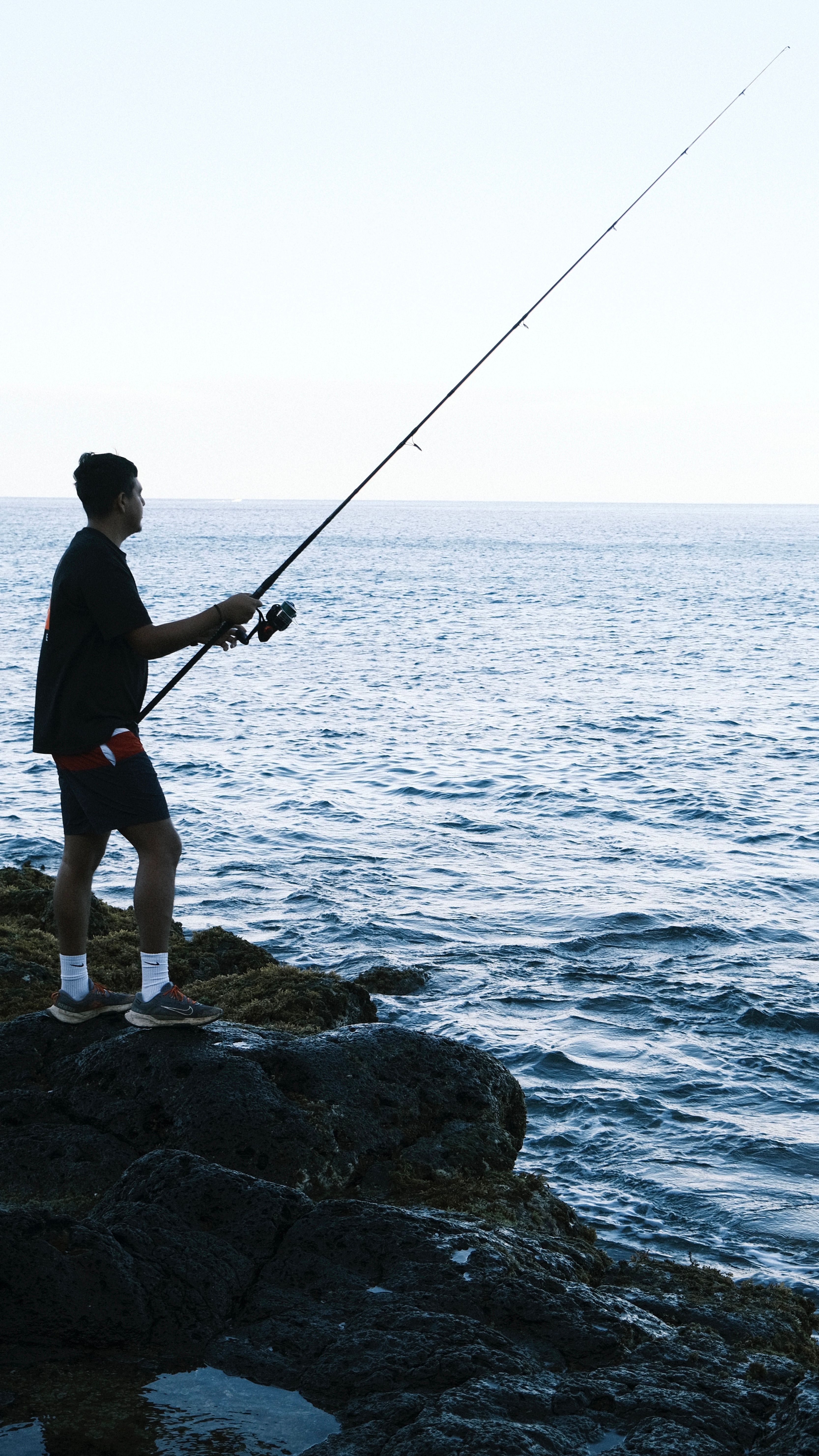Fisherman on rocky coast at sunrise