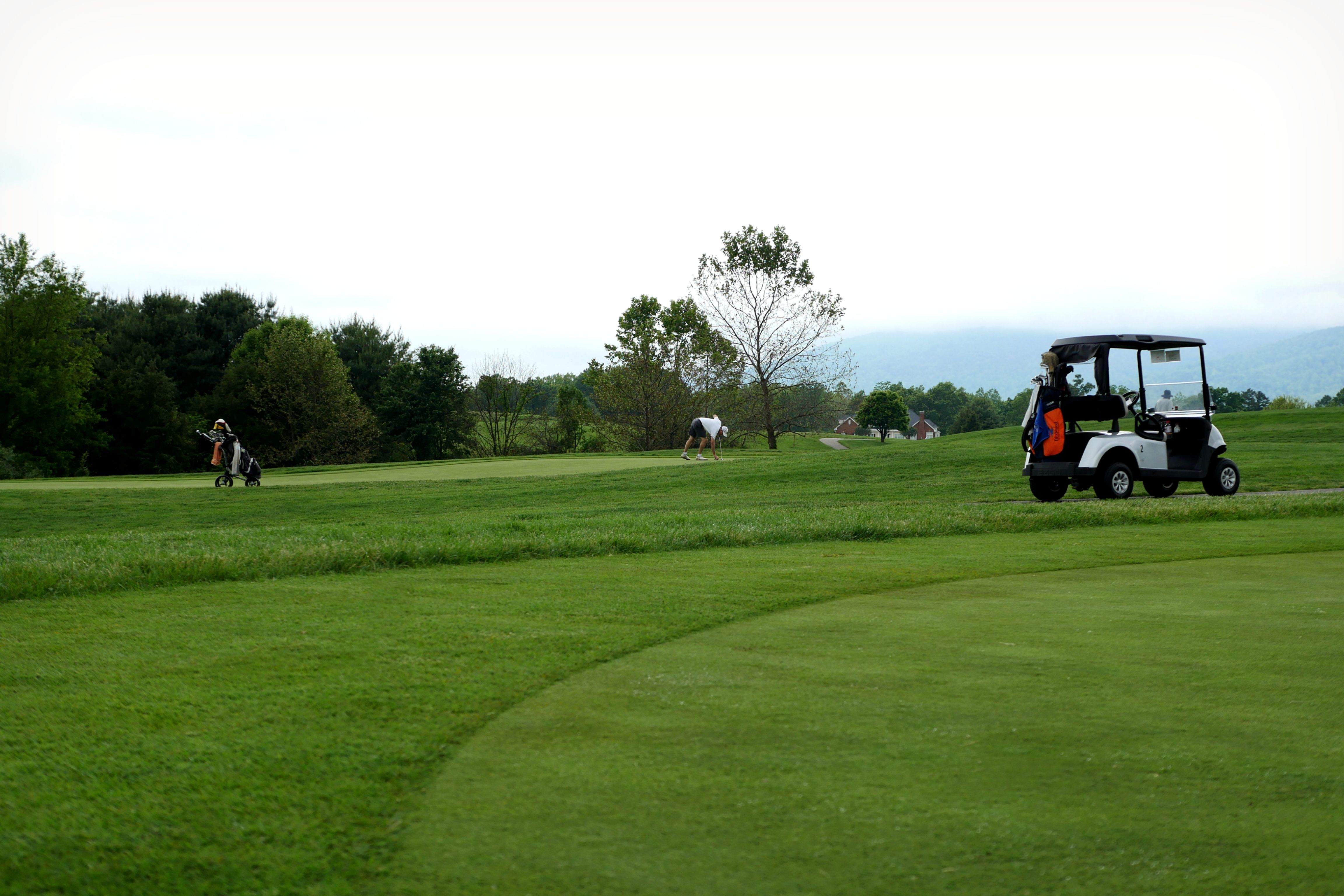 Golfers on a green under a dramatic cloudy sky